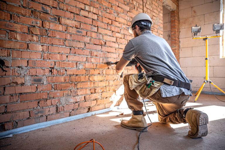A builder works with a drill at a construction site